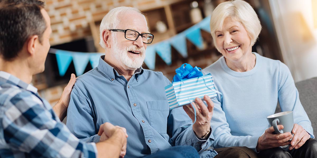 Happy elderly man looking at the birthday present in his hands