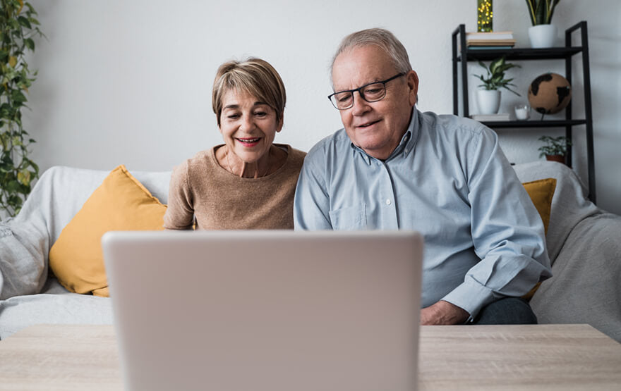 Happy senior couple doing video call at home