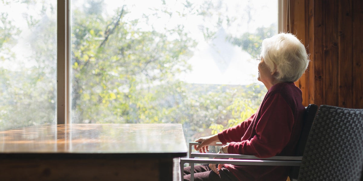 Old woman sitting by a large window