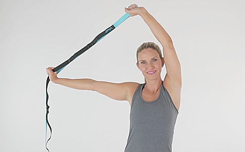 woman stretching arms overhead with stretch strap