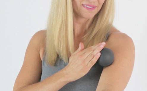 Woman using massage ball to massage her shoulder