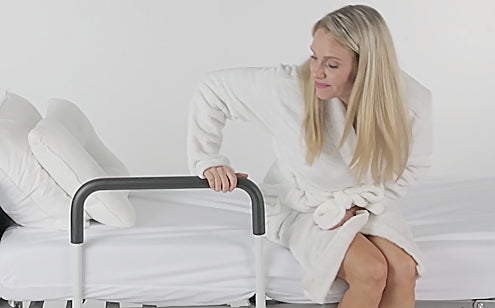 woman using bed rail to stand out of bed