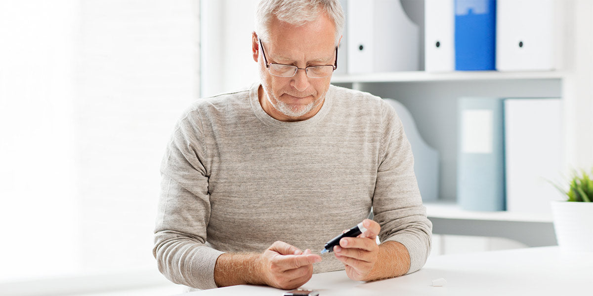 Senior man with glucometer checking blood sugar level at home