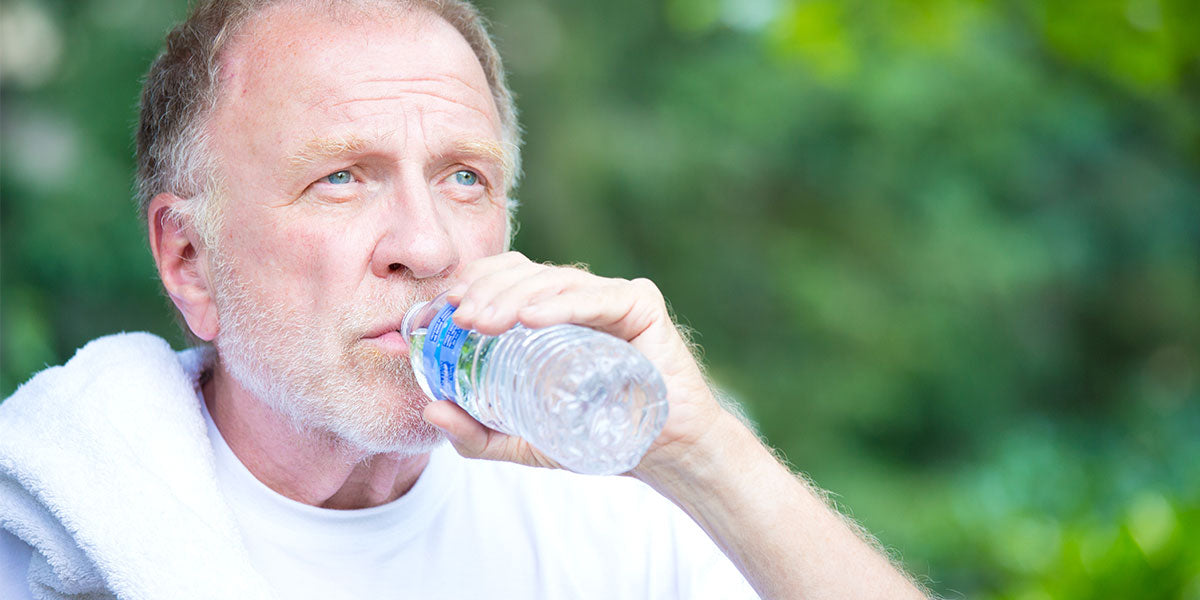 Thirsty senior mature man drinking water outside
