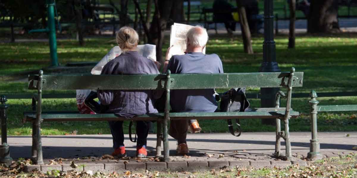 couple reading the newspaper on bench