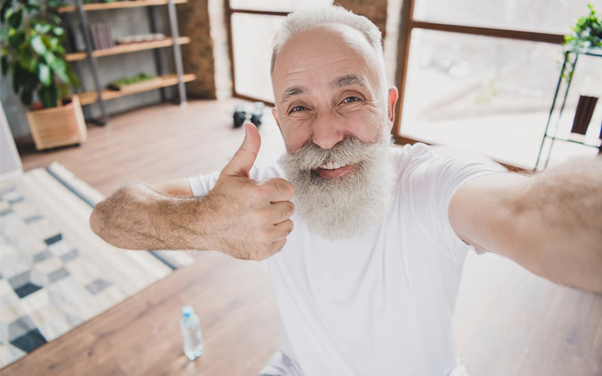 Grey haired retired pensioner smile show thumb up wear sportswear indoors in house