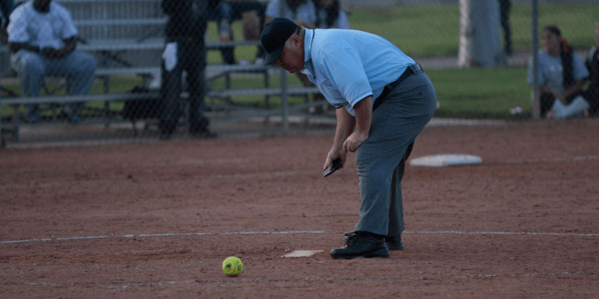 softball umpire brushing base