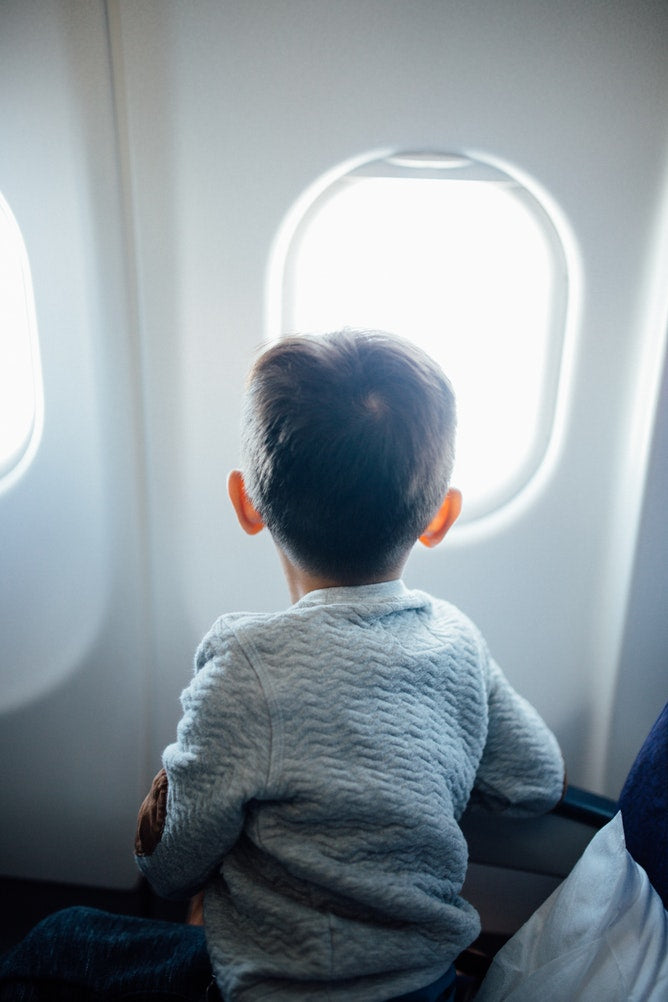 Kid looking out the window from plane