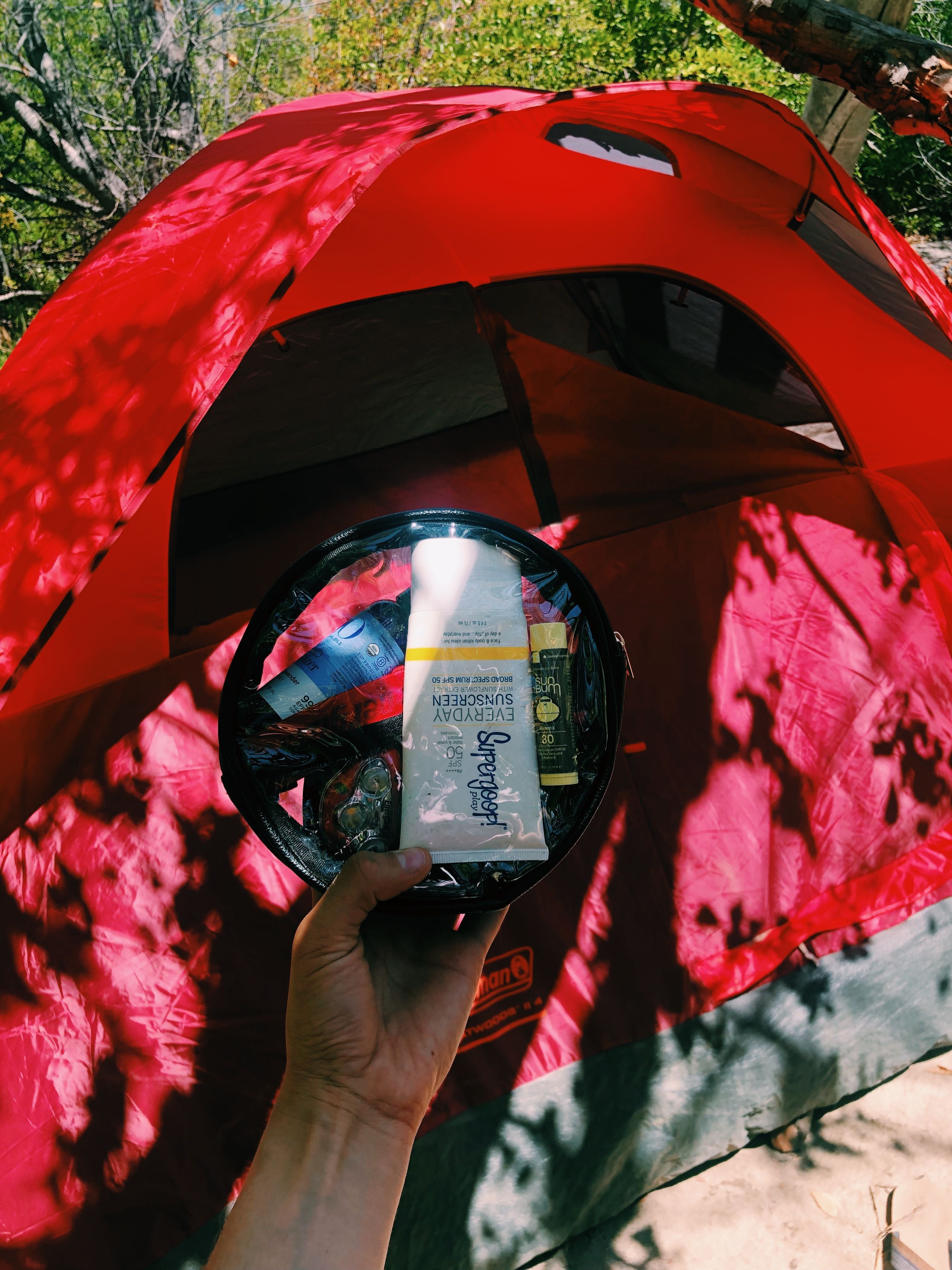 Red tent and a clear circle hygiene pouch for a camping trip