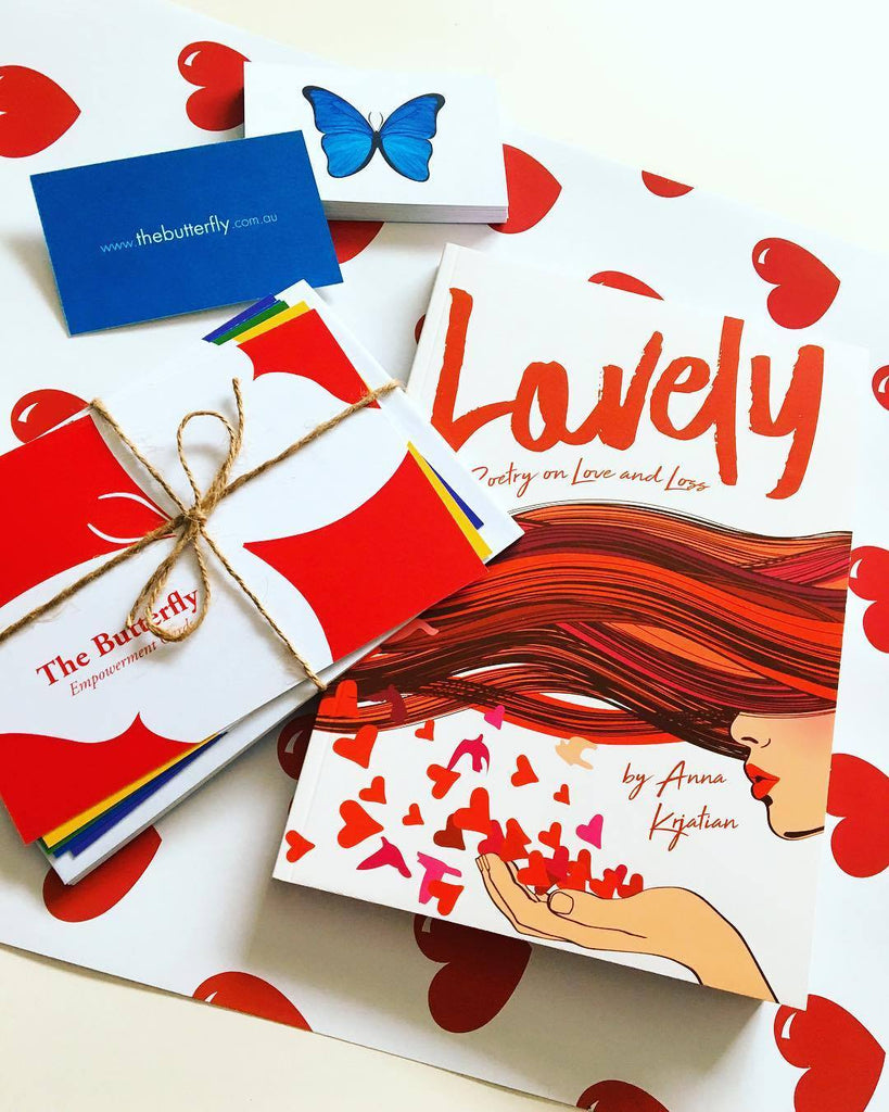 The book "Lovely - Poetry on Love and Loss" and The Butterfly Empowerment Cards and business card, sit on top of the Lovely Wrapping Paper.