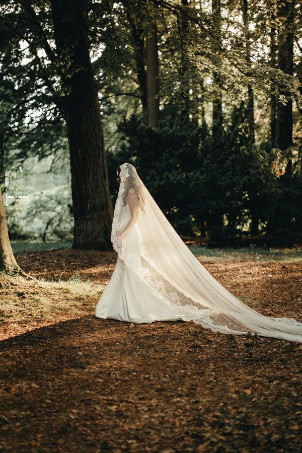 bride walking through the forest with long lace veil