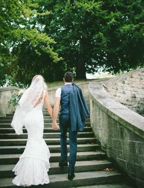 Mantilla Veil bride and groom holding hands walking up stairs