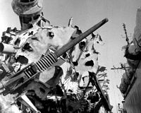 A view of the damaged sustained by the starboard side 3-inch/50-caliber gun aboard the guided missile cruiser USS BELKNAP (CG-26). The BELKNAP was heavily damaged and caught fire when it collided with the aircraft carrier USS JOHN F. KENNEDY (CV 67) during night operations on Nov 22, 1975.