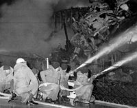 Firefighters aboard the guided missile destroyer USS CLAUDE V. RICKETTS (DDG 5) direct spray from their hoses onto a fire aboard the guided missile cruiser USS BELKNAP (CG 26). The BELKNAP was heavily damaged and caught fire when it collided with the aircraft carrier USS JOHN F. KENNEDY (CV 67) during night operations. - 1975