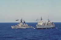 A port bow view of the fast combat support ship USS SEATTLE (AOE 3), right, participating in an underway replenishment with the guided missile cruiser USS BIDDLE (CG 34). A CH-46 Sea Knight helicopter is participating in a vertical replenishment between the two ships. - 1987