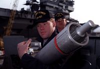 A sailor from the Super Rapid Bloom Offboard Chaff (SRBOC) reloading crew of the aircraft carrier USS JOHN F. KENNEDY (CV-67) carries a chaff cartridge during training aboard the guided missile cruiser USS BIDDLE (CG-34). - 1992
