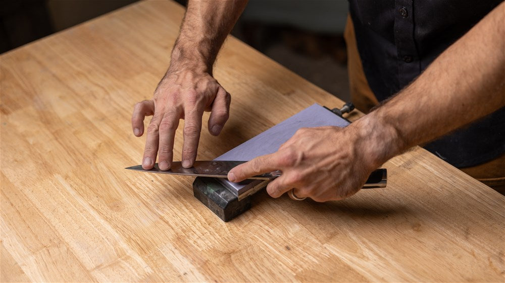 A kitchen knife being sharpened on a water stone.