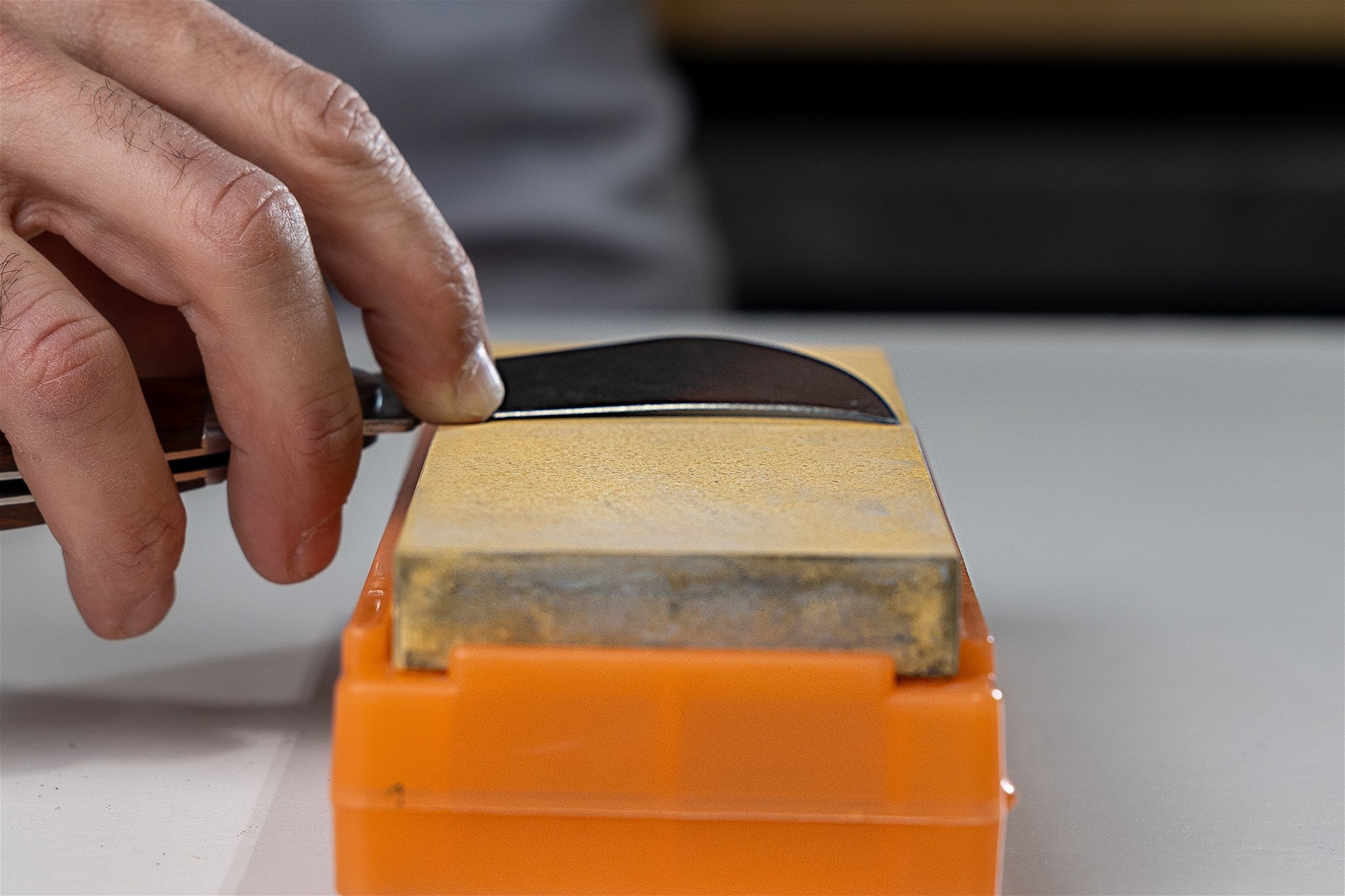 A curved knife on a water stone, showing that the curve prevents the edge from touching the surface of the stone