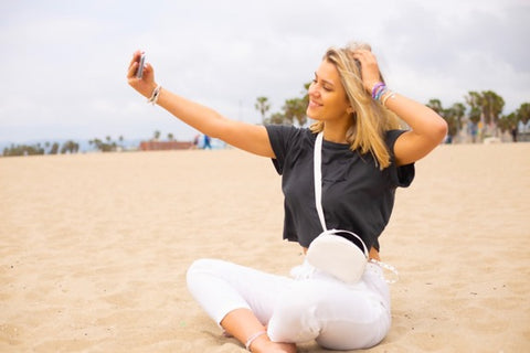 girl on beach taking a selfie with womens beach bracelets