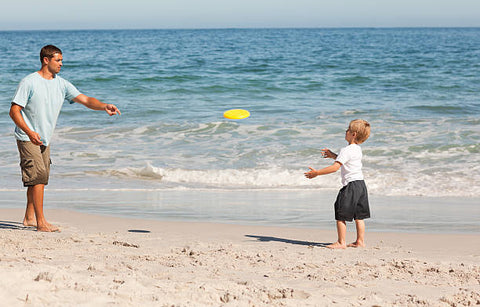 an image of son and father playing frisbee at the beach
