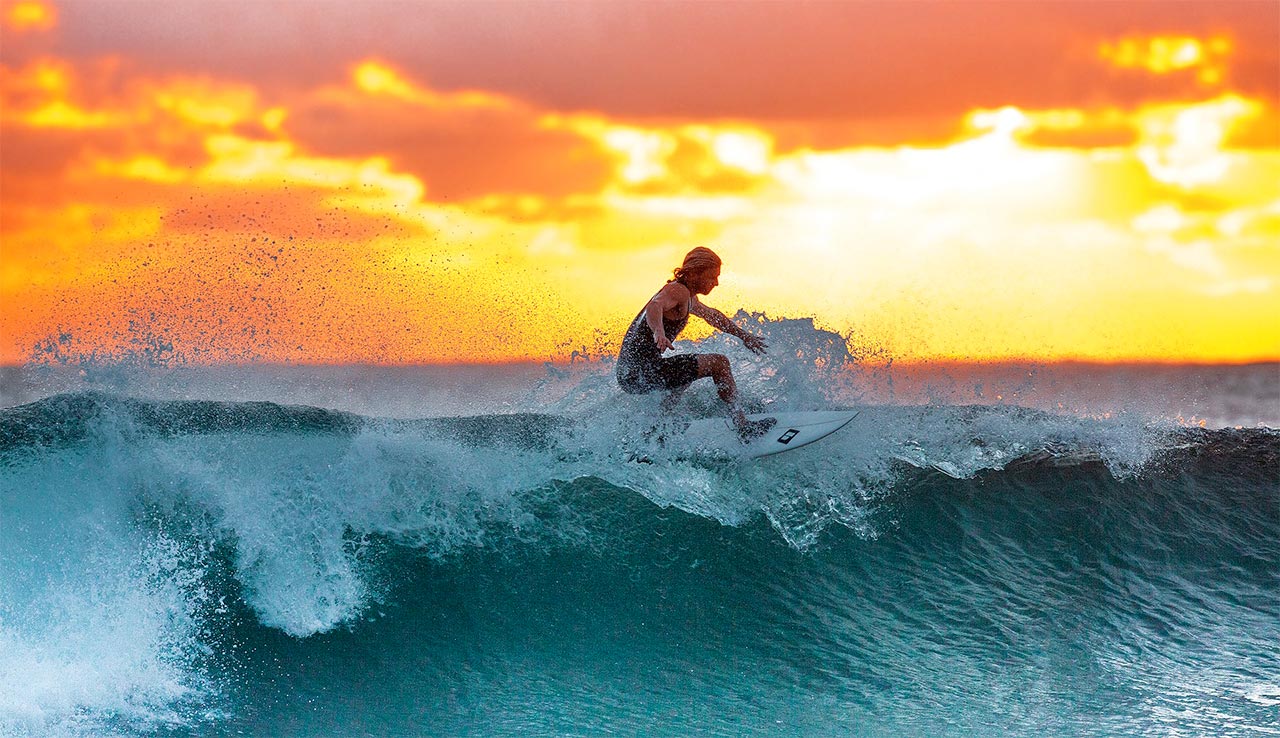 Surfing a wave in the warm ocean during a sunset