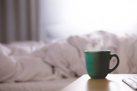 green-mug-of-coffee-on-bedside-table