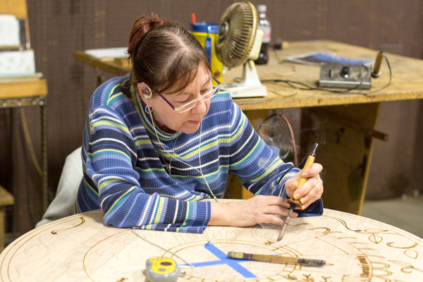 Artist burning an illustration into a Sticks table. 