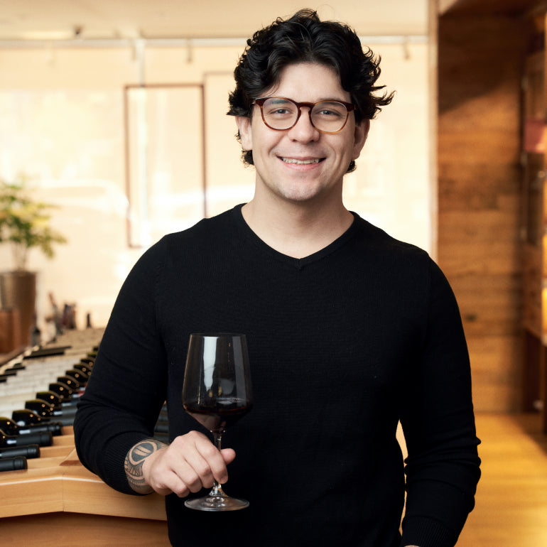 Diego Bonassa, diretor da Grand Cru, posa em uma loja da rede com uma taça de vinho na mão