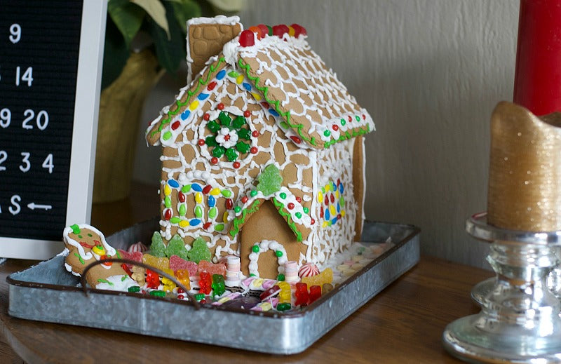 Make a sweet focal point with my gingerbread cottage holiday centerpiece to enjoy all season. Store bought gingerbread house is set in a metal tray for a vintage look that's easy to move around! #gingerbread #gingerbreadhouse #gingerbreadcottage #holiday #centerpiece #Christmas #familydinner