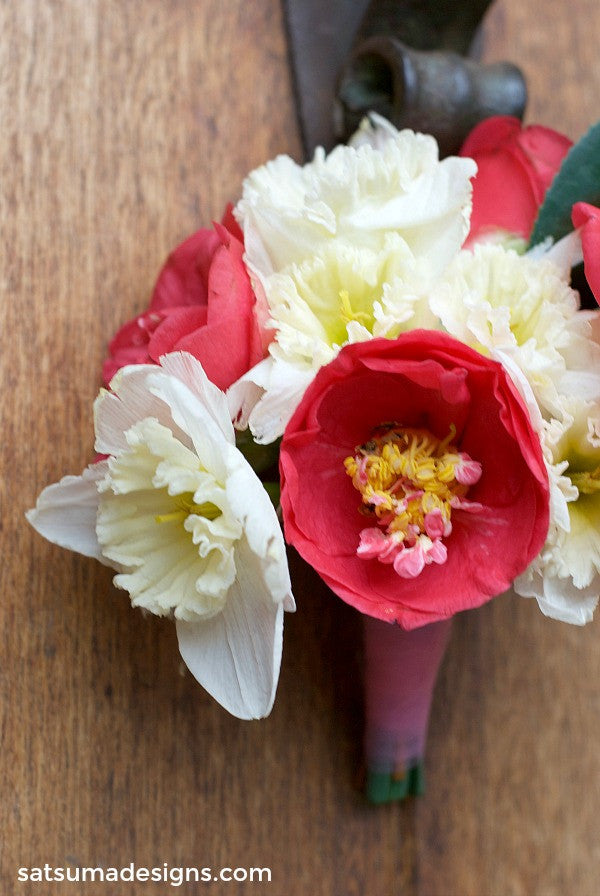 Daffodils and camelia flowers in a bouquet hanging from a door handle