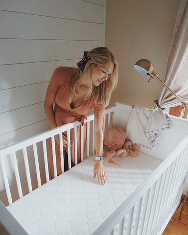 pregnant woman feeling baby pillow in crib