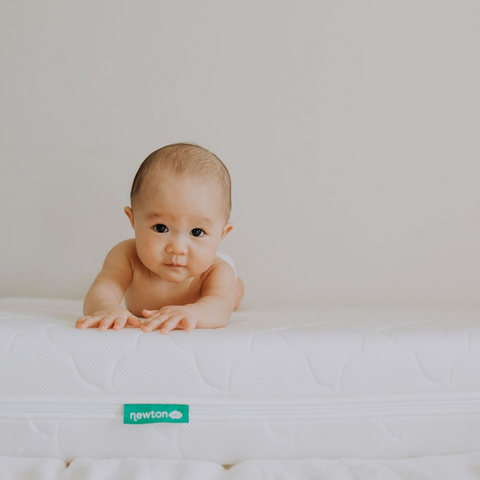 baby laying on a newton baby crib mattress