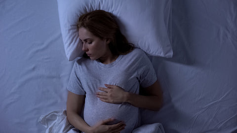 top view of woman sleeping holding her pregnant belly