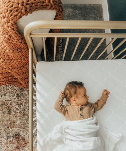 Wide awake baby going through a sleep regression lying in a crib
