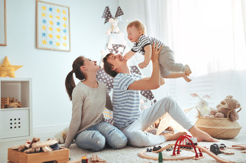 new parents playing with baby on the floor in a small nursery