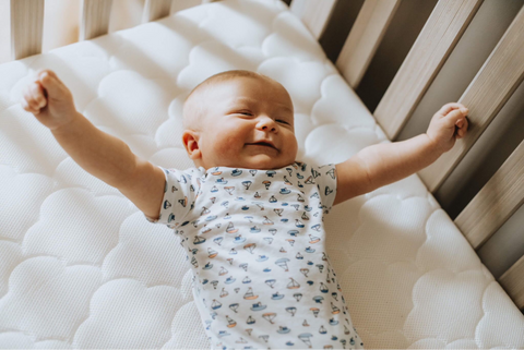 smiling baby stretched out in a crib