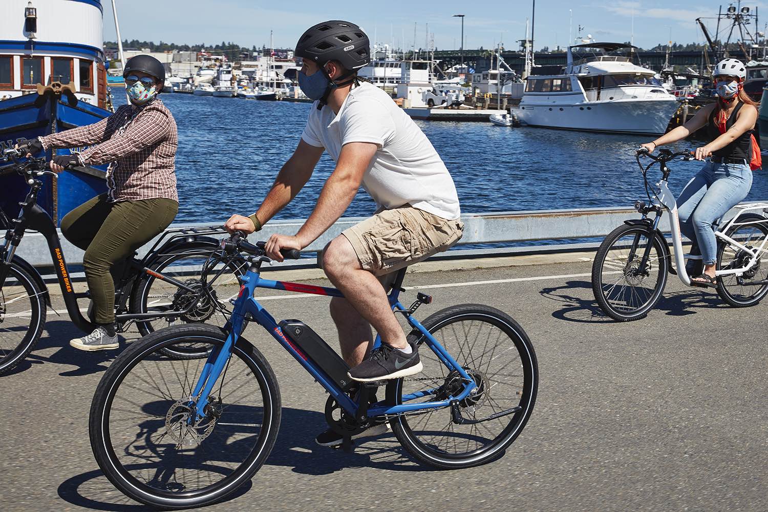 Three friends ride their electric bikes along the boardwalk.
