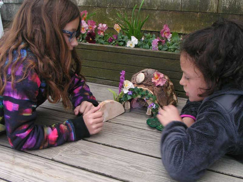 Two young girls playing with a fairy house