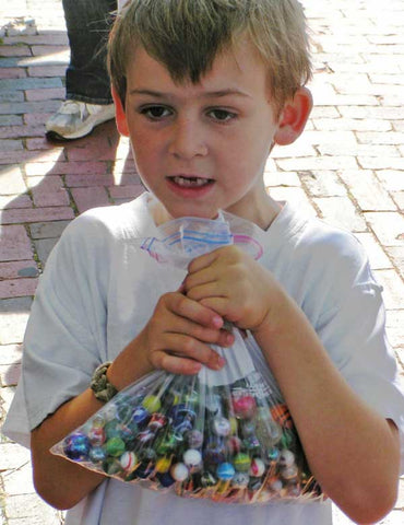 A little boy holding a bag of marbles