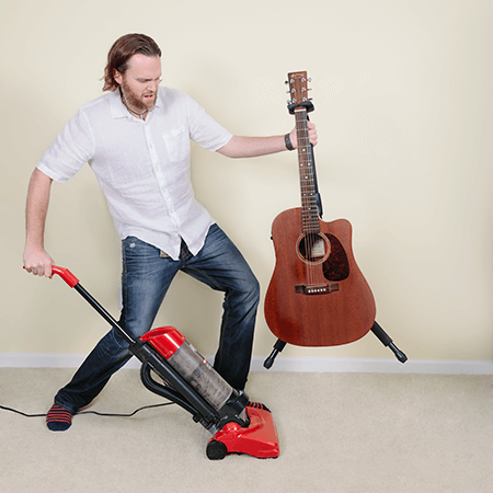 Man inconvenienced by having to lift up guitar and guitar stand to vacuum underneath. 