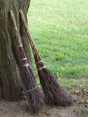 Pair of besoms leaning against a tree