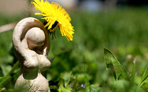 Goddess figure holding a dandelion