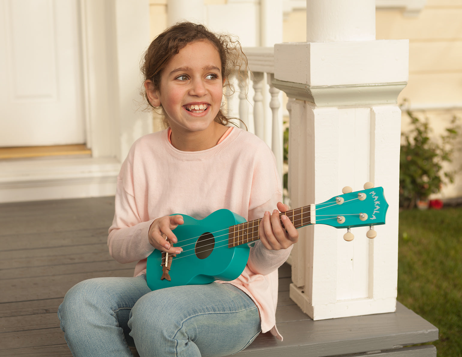 Child Playing a Kala Brand Music Co. Makala Shark Blue Mako Soprano Ukulele on a Porch