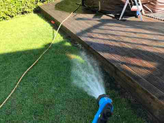 Drenching grass with water prior to softwashing wooden decking with Benz Perma Cleanze