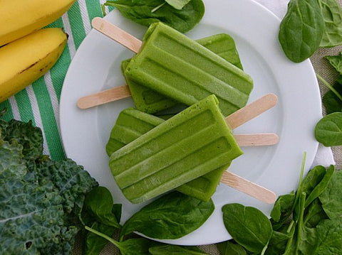 Green popsickles on a white plate, spinach and bananas