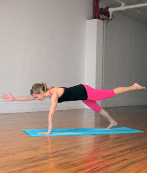woman planking on yoga mat right hand and left leg out