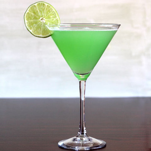 Green juice in a martini glass with a lemon wedge on  brown table