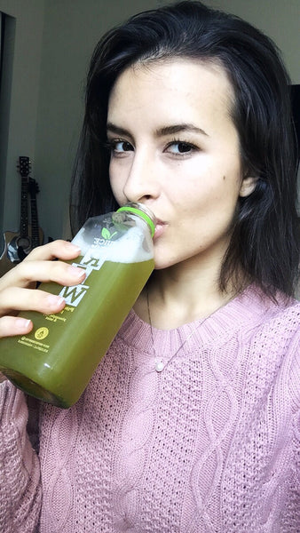 woman drinking juice wearing pink sweather