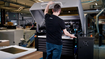 Man standing in front of a large art printer, showing our production