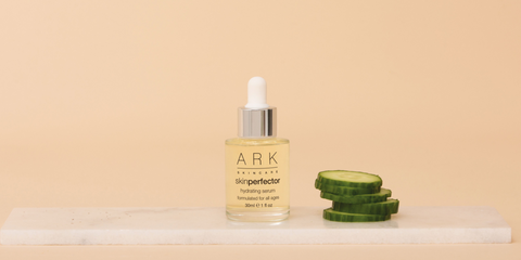 Image: ARK Skincare's Hydrating Serum in glass bottle with pipette next to slices of cucumber sitting on a marble slate. 